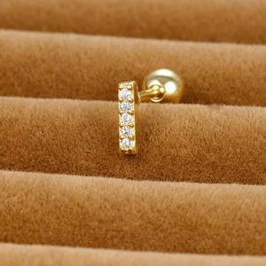 Macro shot of minimalist gold stud earring with five sparkling cubic zirconia stones
