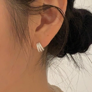 Minimalist 925 silver stud earrings with three rows of zircons shown on a model ear