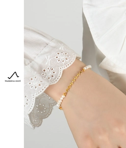 Detail showing the polished gold chain and freshwater pearls on a stainless steel bracelet