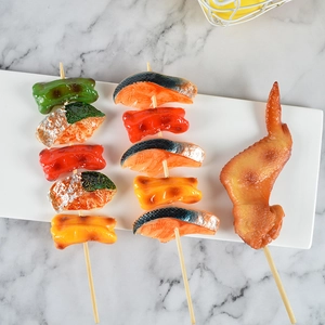 Spiedini barbecue artificiali con polpette di pesce e ali di pollo su vassoio in ceramica