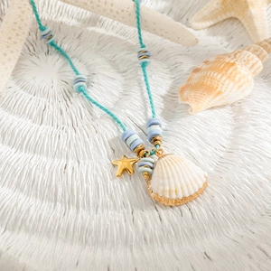 Detailed close-up of woven blue cord necklace with golden starfish and shell charms