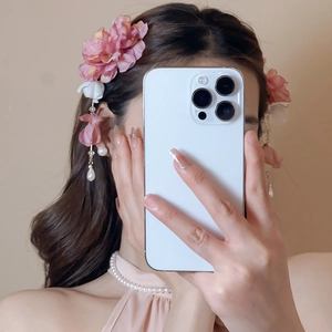 Détail d'une pince à cheveux fleur en tissu rose avec pampilles de perles blanches