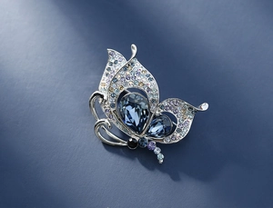 Close-up of butterfly brooch with dark blue pear-shaped crystals and colorful rhinestones
