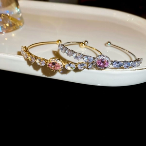 Detail of gold and silver open bangles with pink oval stones and zircon accents