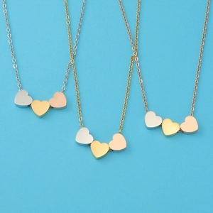 Detailed view of triple heart pendants in silver, gold, and rose gold on cable chains