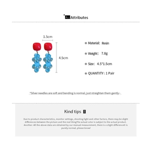 Detailed view of red resin square earrings with blue bead tassels and silver posts