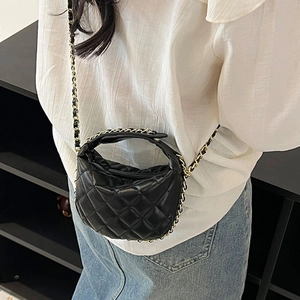 Mini black quilted leather crossbody bag with metal chain strap worn by a model