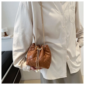 Detailed view of brown quilted bucket bag with gold chain and pearl tassel detail