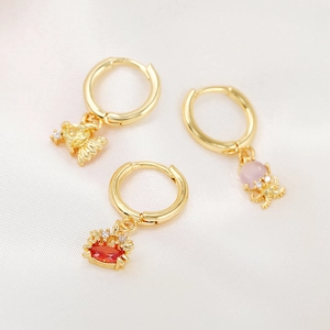 Golden sea animal earrings featuring fish, octopus, and crab on white satin fabric