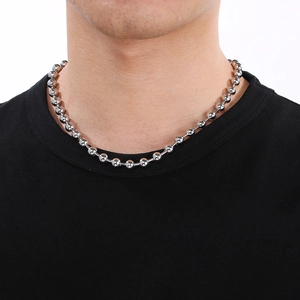 Collier à billes en acier inoxydable argenté porté au cou sur fond blanc brillant