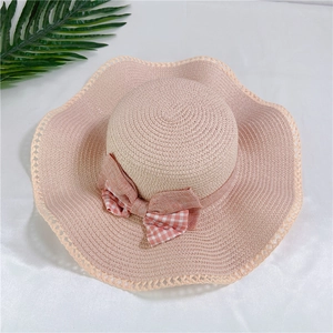 Dettaglio cappello di paglia a tesa larga ondulata con fiocco a quadretti rosa