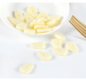 Macro detail of miniature PVC garlic slices on a white porcelain plate with a metal fork