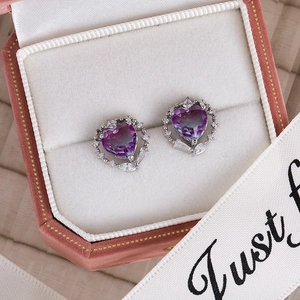 Macro shot of silver heart-shaped studs with purple gradient zircon in a velvet gift box