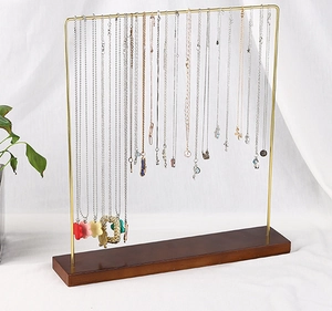 Detail showing golden U-shaped metal rack with wooden base holding various necklaces