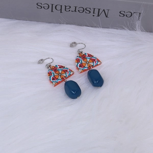 Detail of vintage geometric acrylic earrings with blue beads on white fur background