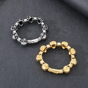 Detail of silver and gold punk skull link bracelets on a matte black background