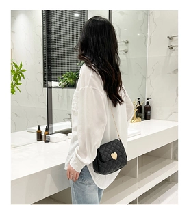 Chic black quilted crossbody bag featuring a golden heart-shaped lock and chain strap