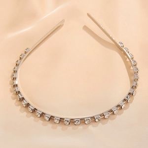 Detail of silver headband with square clear rhinestones on beige silk background