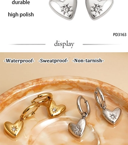 Close-up of heart earrings with star engraving and cubic zirconia in gold and silver