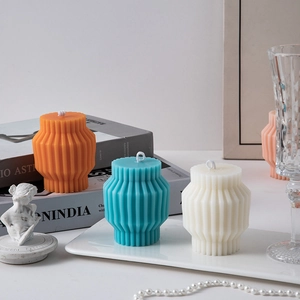 Close-up of geometric striped lantern candles in orange, blue and white home decor