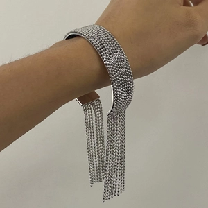 Macro shot of silver beaded open bangle featuring long metallic tassel chains for women