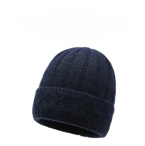 Detailed view of navy blue knitted beanie hat with a small metal diamond logo emblem