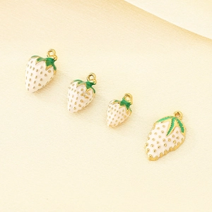 Detailed close-up of strawberry enamel pendants with gold edges for DIY jewelry making