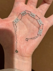 Detailed macro view of the double-sided flower hollow bracelet with logo brand tag