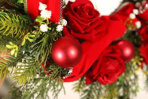 Macro detail of red rose petals and glossy ornaments on a festive Christmas wreath