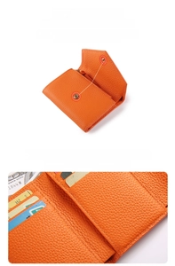 Macro shot of orange pebble leather wallet showing snap closure and internal card slots
