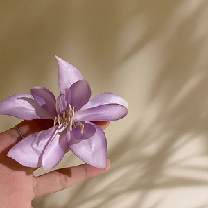 Macro detail of purple fabric hibiscus clip with realistic silk petals and yellow stamen