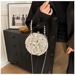 Close-up of silver metal rose shaped evening clutch with beaded handle and chain strap
