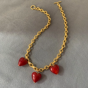 Detail of gold-plated chain necklace with three translucent red heart pendants and OT clasp