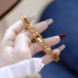 Close-up of gold chain watch band with tiger eye stones on a female wrist