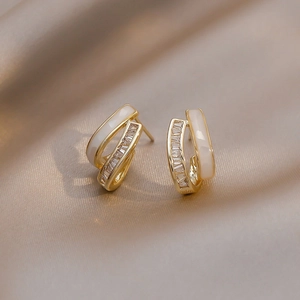 Macro detail of double-layered C-shape earrings with baguette zircons and white shell