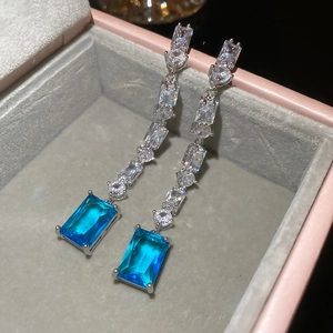 Close-up of 18K gold plated drop earrings with blue rectangular gem and clear zircons
