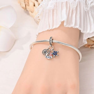 Close-up of silver ocean charm bracelet featuring rudder, sailboat, and starfish pendants