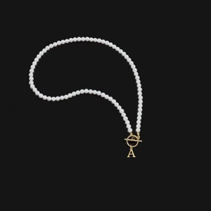 Elegant pearl necklace with gold OT buckle and letter A pendant on black background