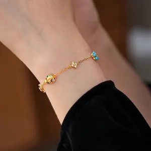 Luxurious 18K gold charm bracelet featuring ladybug and floral pendants on wrist