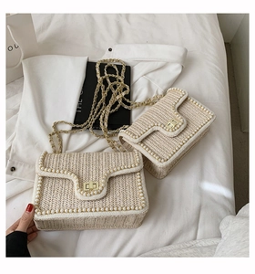 Close-up of woven straw bag featuring pearl trim and gold metal buckle detail