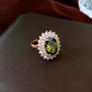 Macro shot of oval green gemstone ring with white zircon halo in gold finish