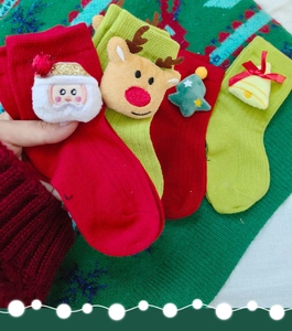 Detail of 3D plush Christmas socks with Santa and reindeer ornaments in red and green