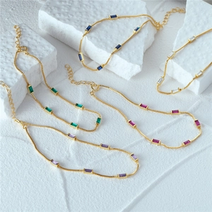 Detail of five gold bracelets with rectangular colorful zircon gemstones on stone