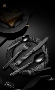 Detail of black stainless steel cutlery set with vintage ribbed handles on a stone plate