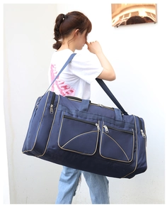 Detail of a large navy blue travel bag with gold piping and multiple storage pockets