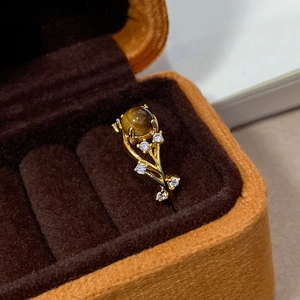 Close-up of gold plated tiger eye ring with zircon accents in a brown velvet jewelry box
