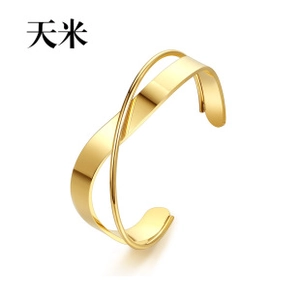Detail of cross-layered 18K gold-plated irregular open bangle with high-polished finish