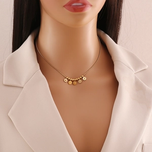 Detailed view of a gold beaded necklace with flower charms worn on a model's neck