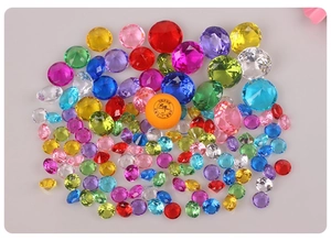 Macro detail of large colorful acrylic crystal diamonds with a yellow ping pong ball for scale