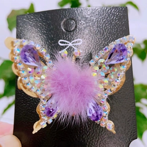 Detail of a moving butterfly hair clip with purple rhinestones and pom-pom wings